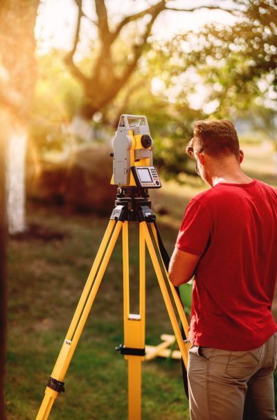 portrait of surveyor caucasian engineer working with total station theodolite at landscaping project